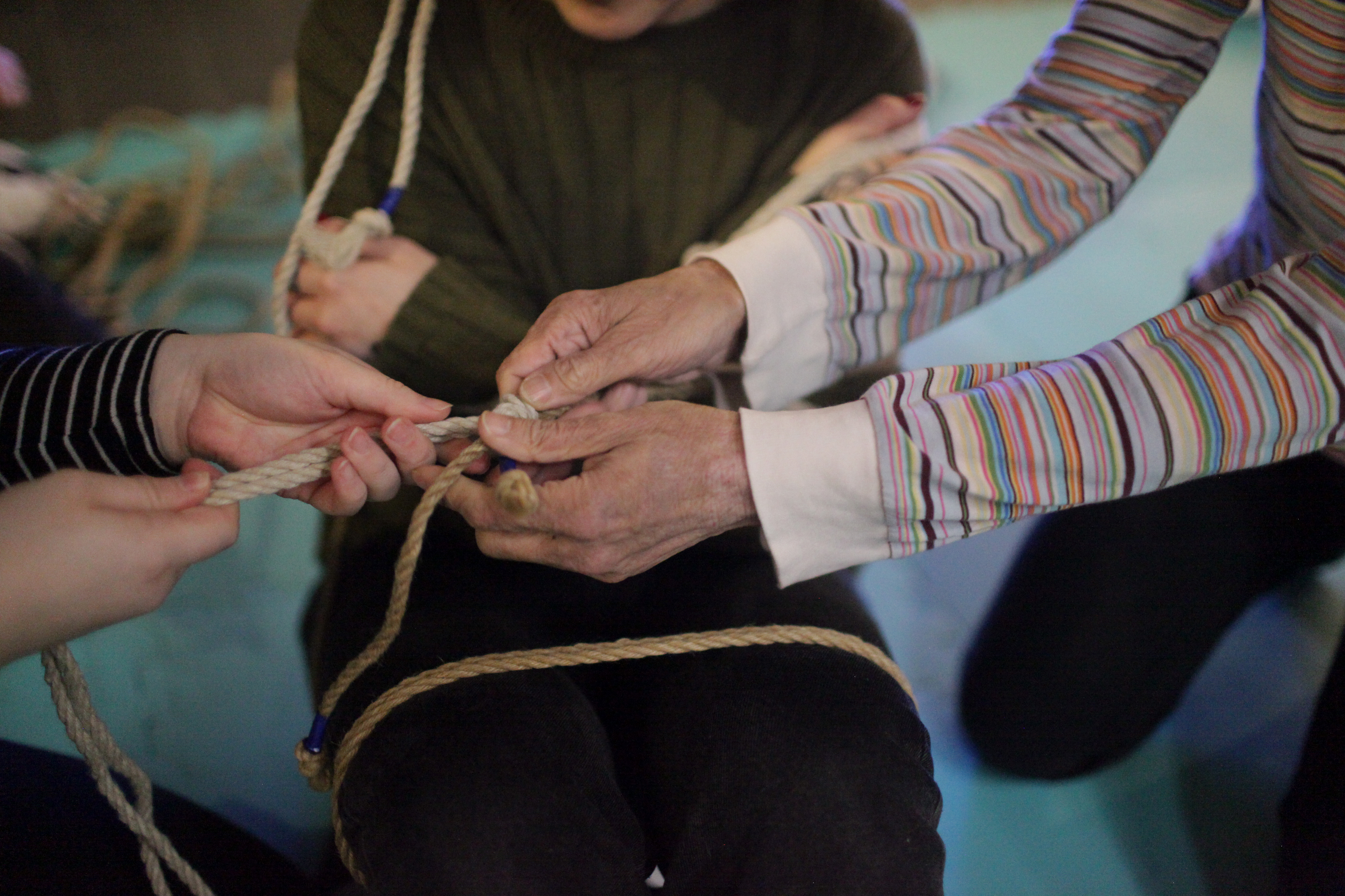 the instructor's hands guid the rope on the participant's hands